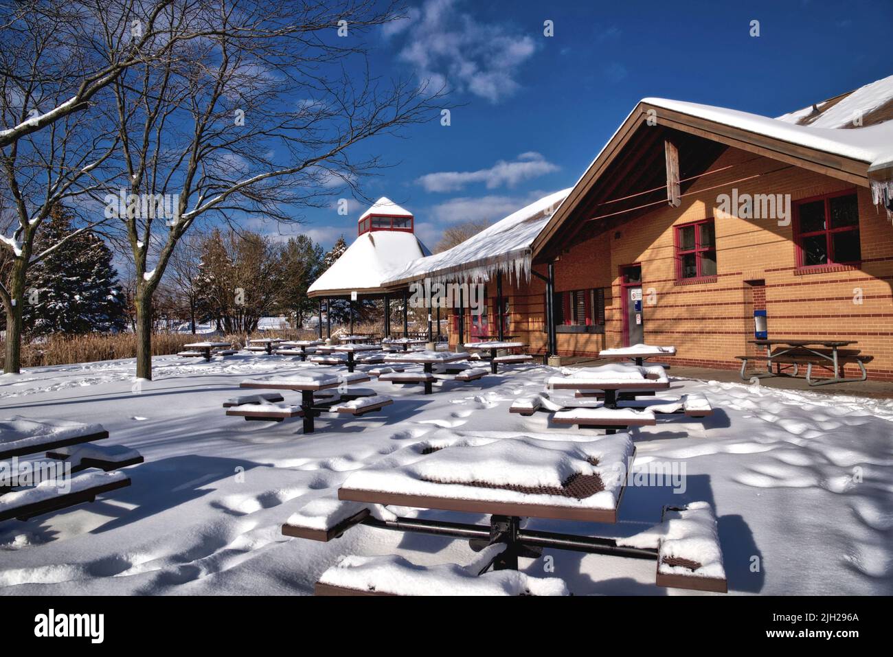 Snow and icicles overhanging the roof of the building.  Deep snow in the park. Stock Photo