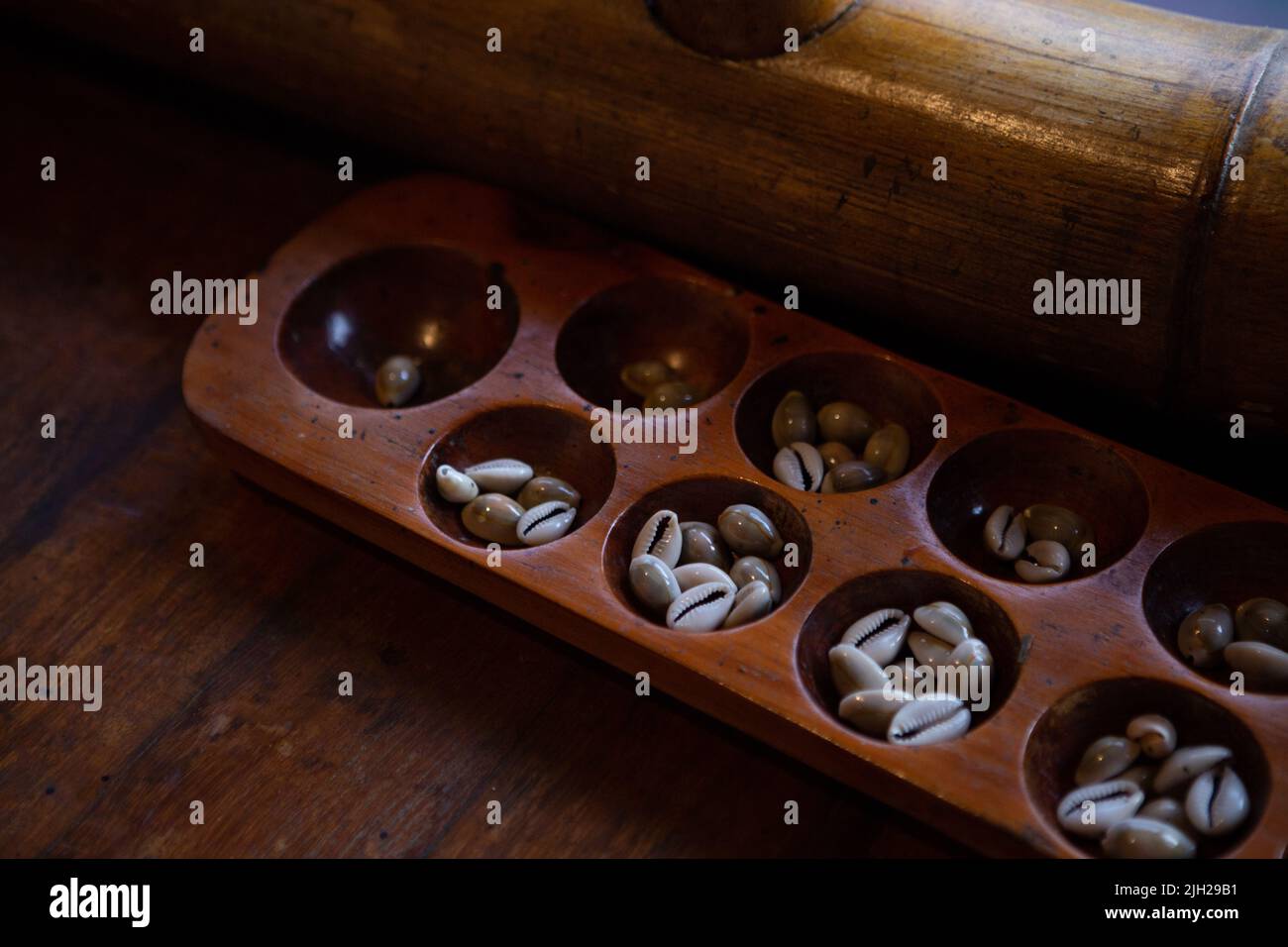 Congklak, a traditional game that uses a wooden board with 14 to 16 round holes Stock Photo