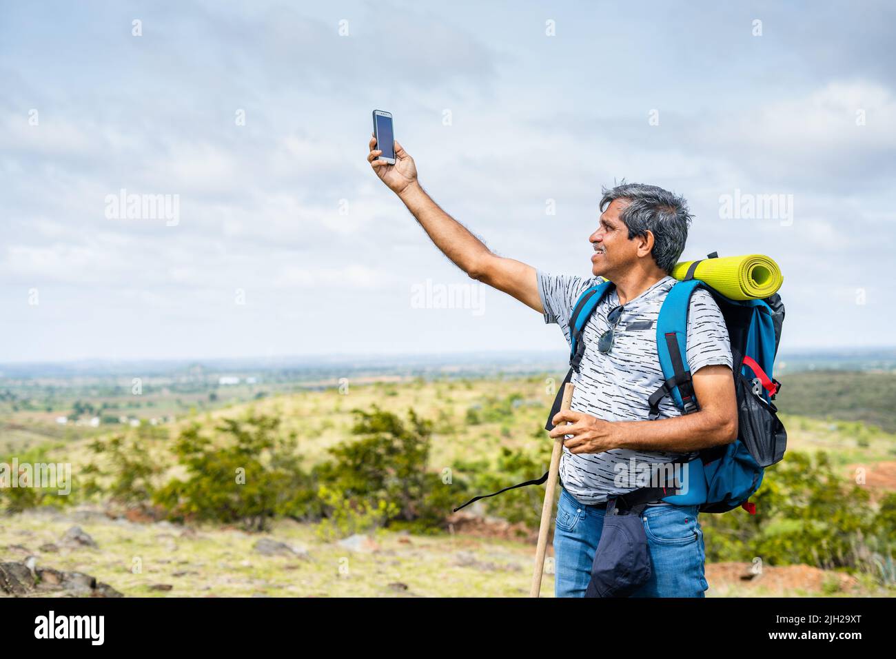 traveler checking mobile phone network reception or connection on hill top during hiking - concpet of wireless technology, internet and communication Stock Photo
