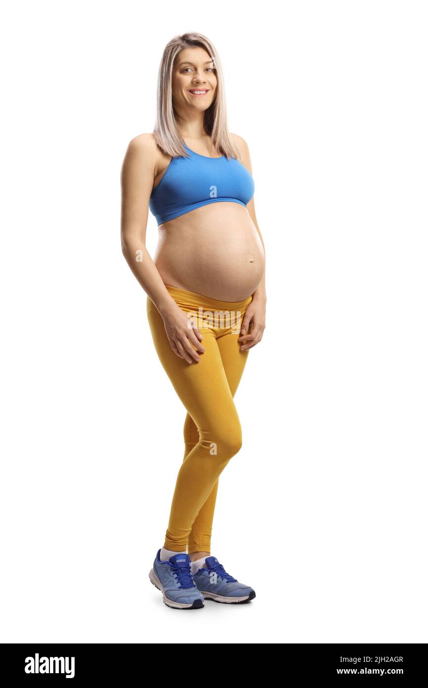 Full length portrait of a pregnant woman in a blue crop top and yellow leggings isolated on white background Stock Photo