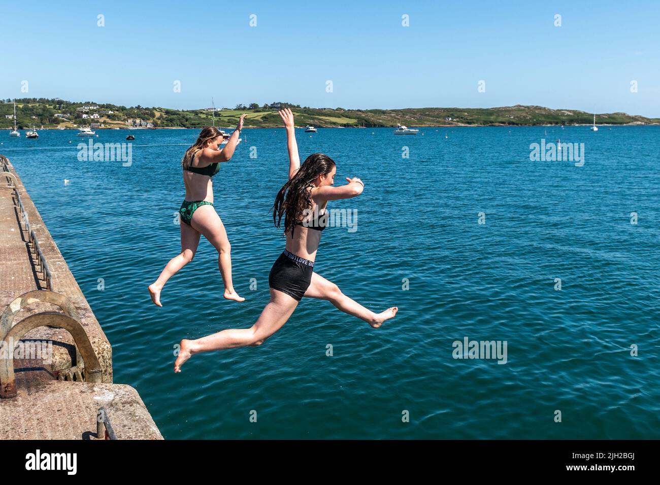 Schull, West Cork, Ireland. 14th July, 2022. The temperatures in West Cork hit 23C today, with many people heading for the coast to cool off. Jumping off Schull pier to cool down were Amelia Davies from Durrus and Amy Wilde from Schull. Credit: AG News/Alamy Live News Stock Photo