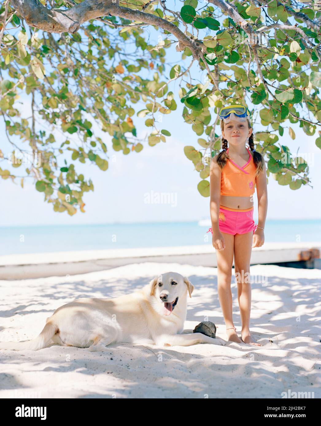 A young girl gets ready to go snorkeling with her dog. On Tiamo Beach at Tiamo Resort. South Andros, Bahamas Stock Photo