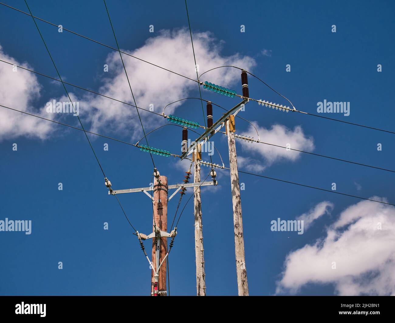 Two electricity supply pylons delivering power through the UK national grid showing power cables, isolators and other equipment. Taken on a sunny day Stock Photo
