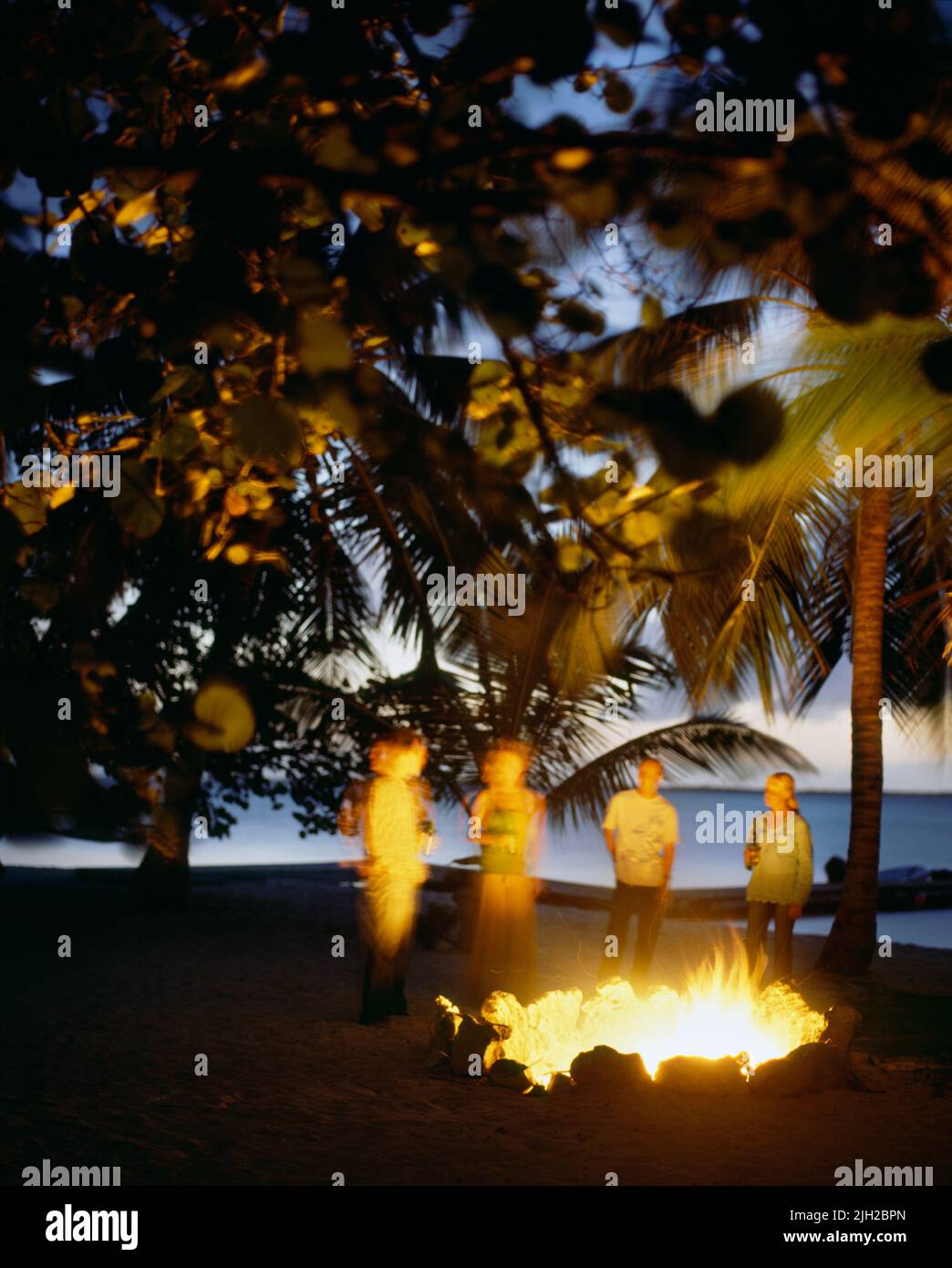 Guests have a drink at sunset by a bonfire on Tiamo Beach. Tiamo Resort. South Andros, Bahamas Stock Photo