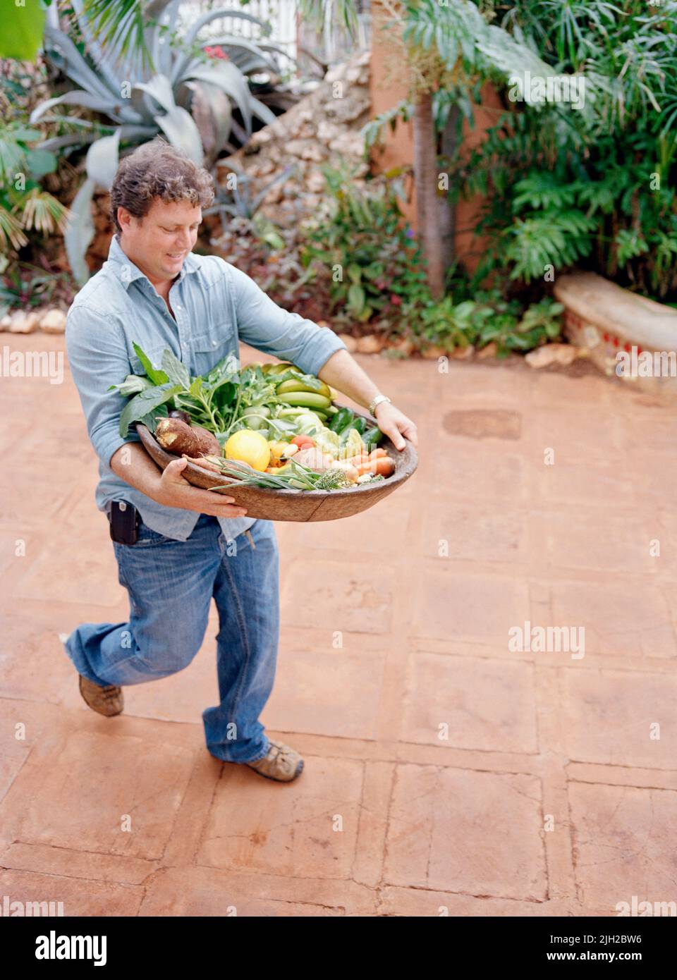 Jake's Resort owner Jason Henzell brings in a platter of organic fruits and vegetables from local farms to the kitchen at Jake's Resort. Jamaica Stock Photo