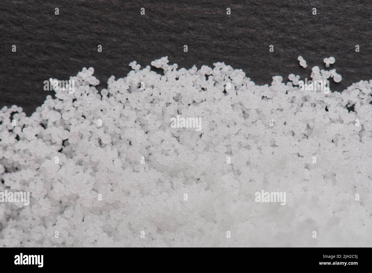 Industrial polystyrene granules white pile on black background Stock Photo