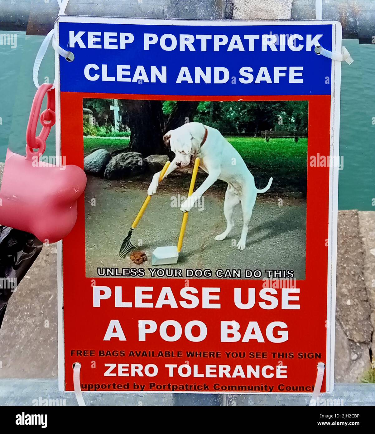 A DOG CLEANING UP ITS OWN MESS - Port Patrick Community Council (Scotland) humorous poster  advising  dog walkers to use the free dog poo bags situated at various points throughout the village. Portpatrick is a village and civil parish in the historical county of Wigtownshire, Dumfries and Galloway, Scotland. Stock Photo