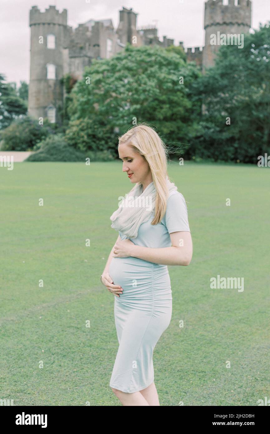 Pregnant woman holds belly in front of Malahide Castle Ireland Stock Photo