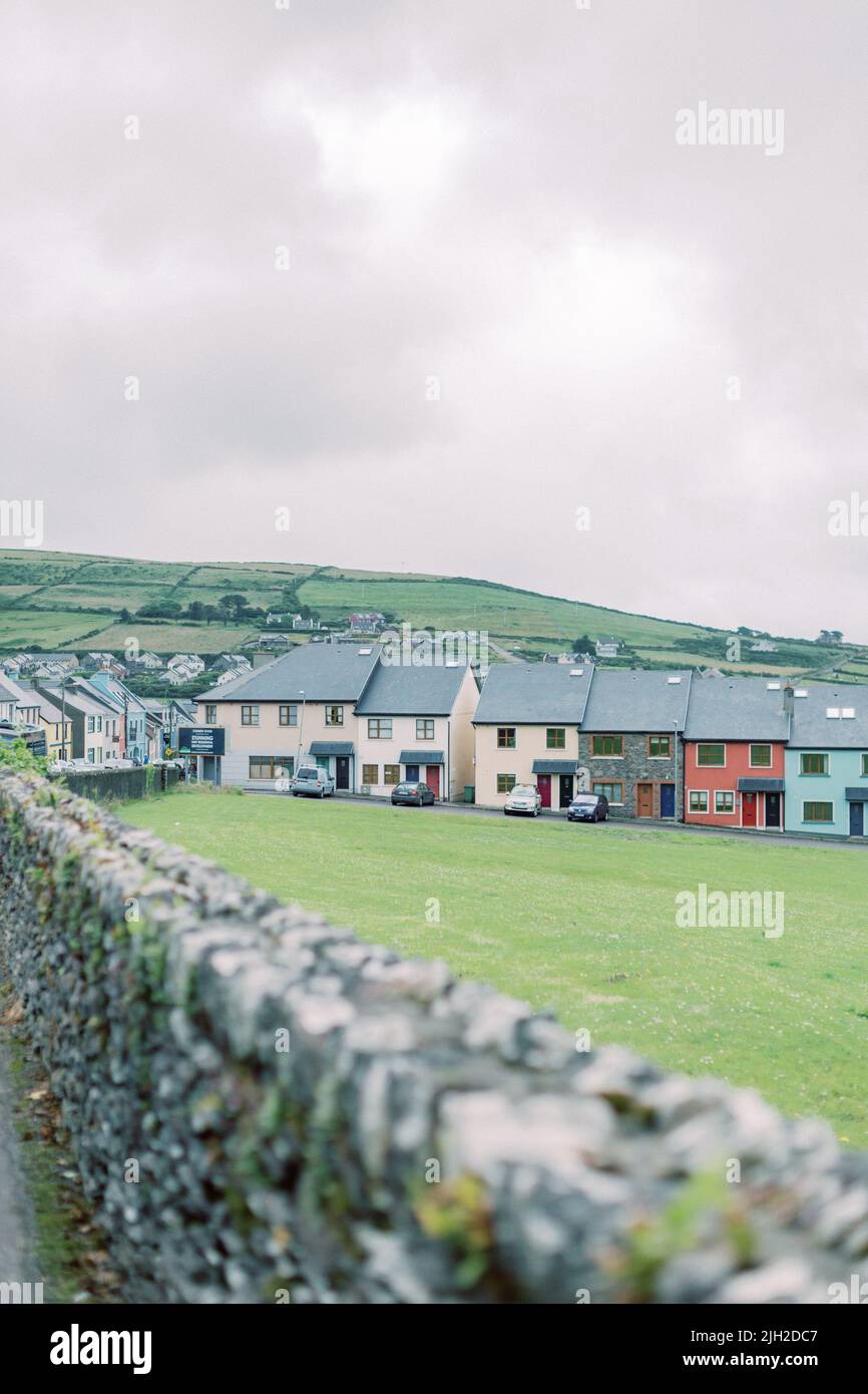 A row of colorful homes behind a stone gate in Dingle, Ireland Stock Photo