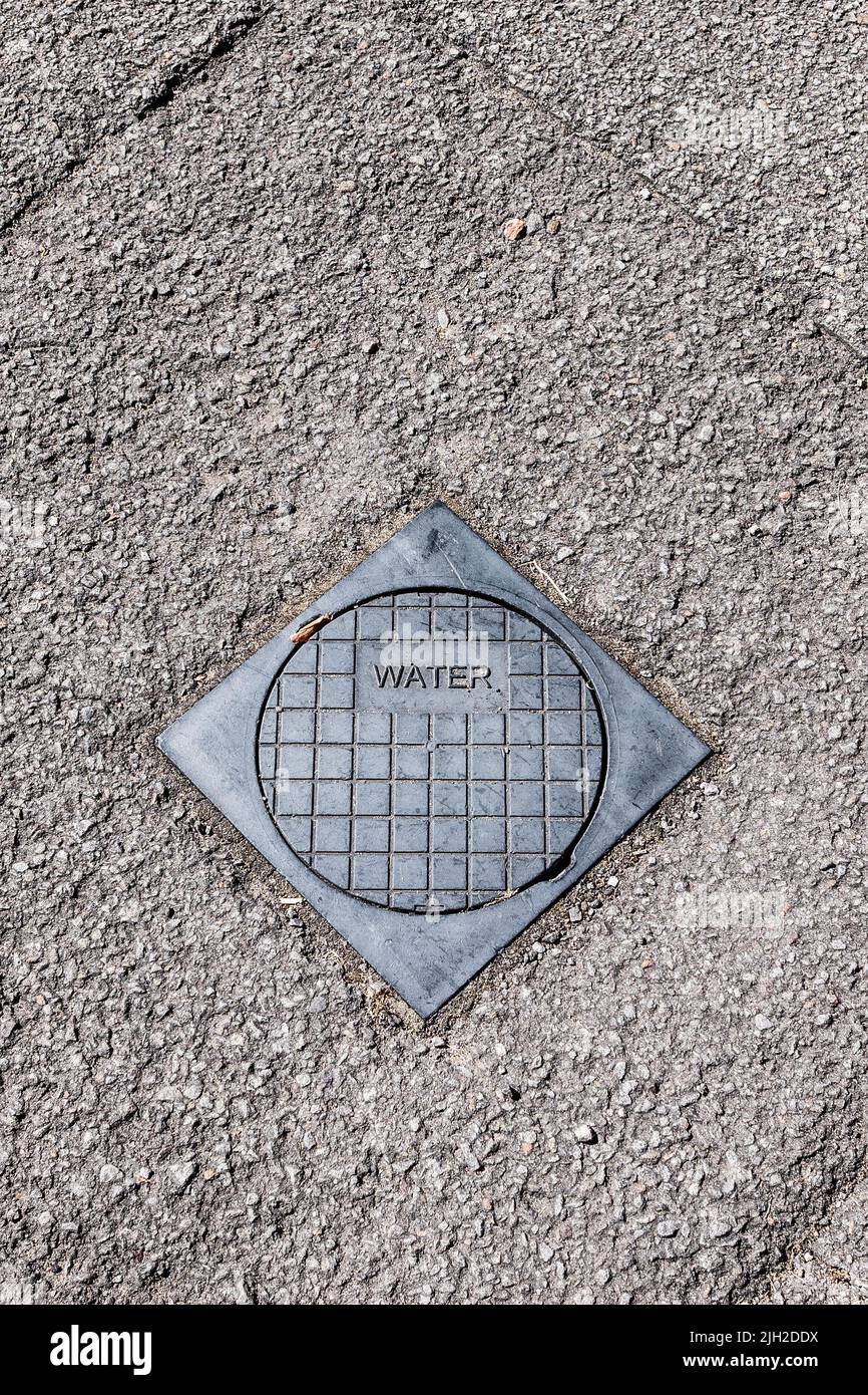 An outside stopcock, stop valve, stop tap metal cover to access and turn off mains water supply. UK water security. Space for text. Stock Photo