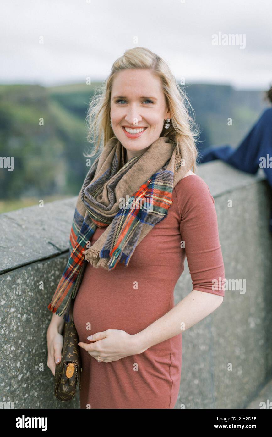 Young, happy pregnant woman at the Cliffs of Moher, Ireland Stock Photo