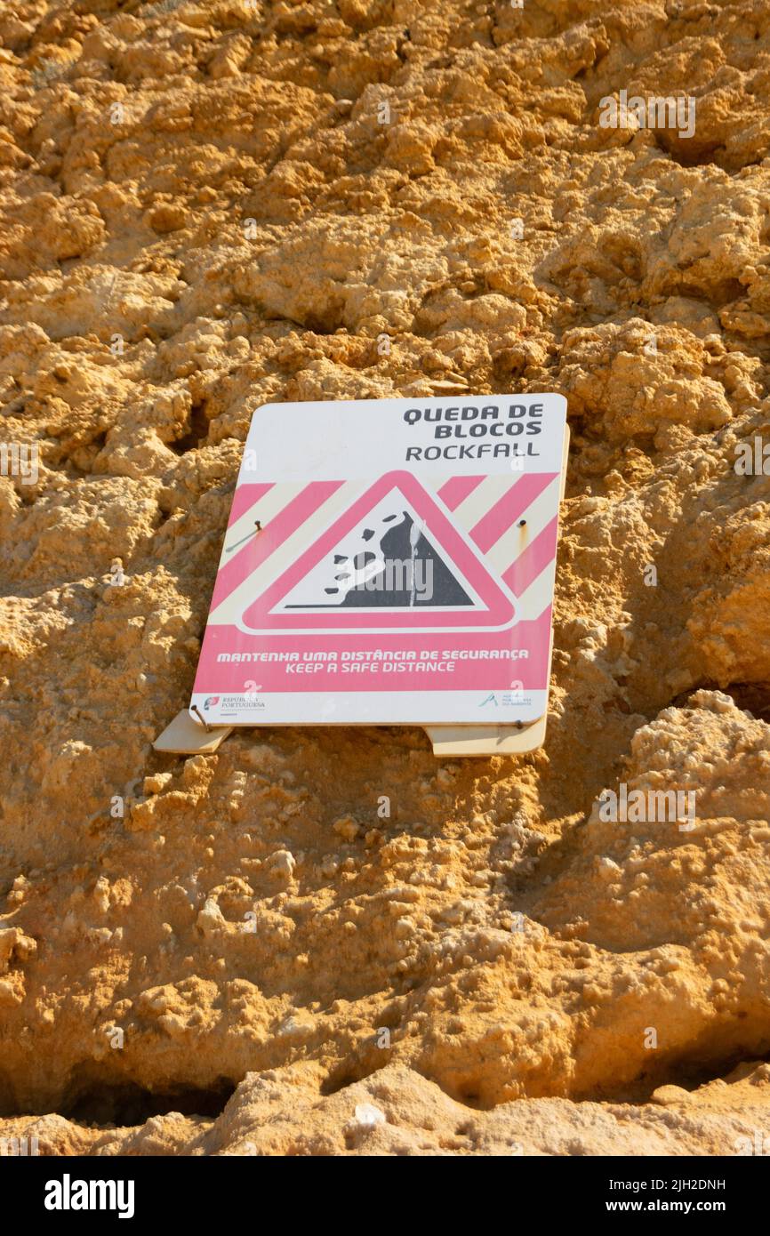 Cliffs rockfall signs in Algarve Portugal. Beach cliffs, rockfall zone on coastal beaches. Dangerous areas on beaches under cliffs. Stock Photo