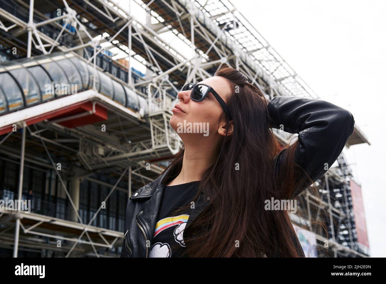 A girl in a leather jacket and glasses in front of the Pompidou Center in Paris Stock Photo