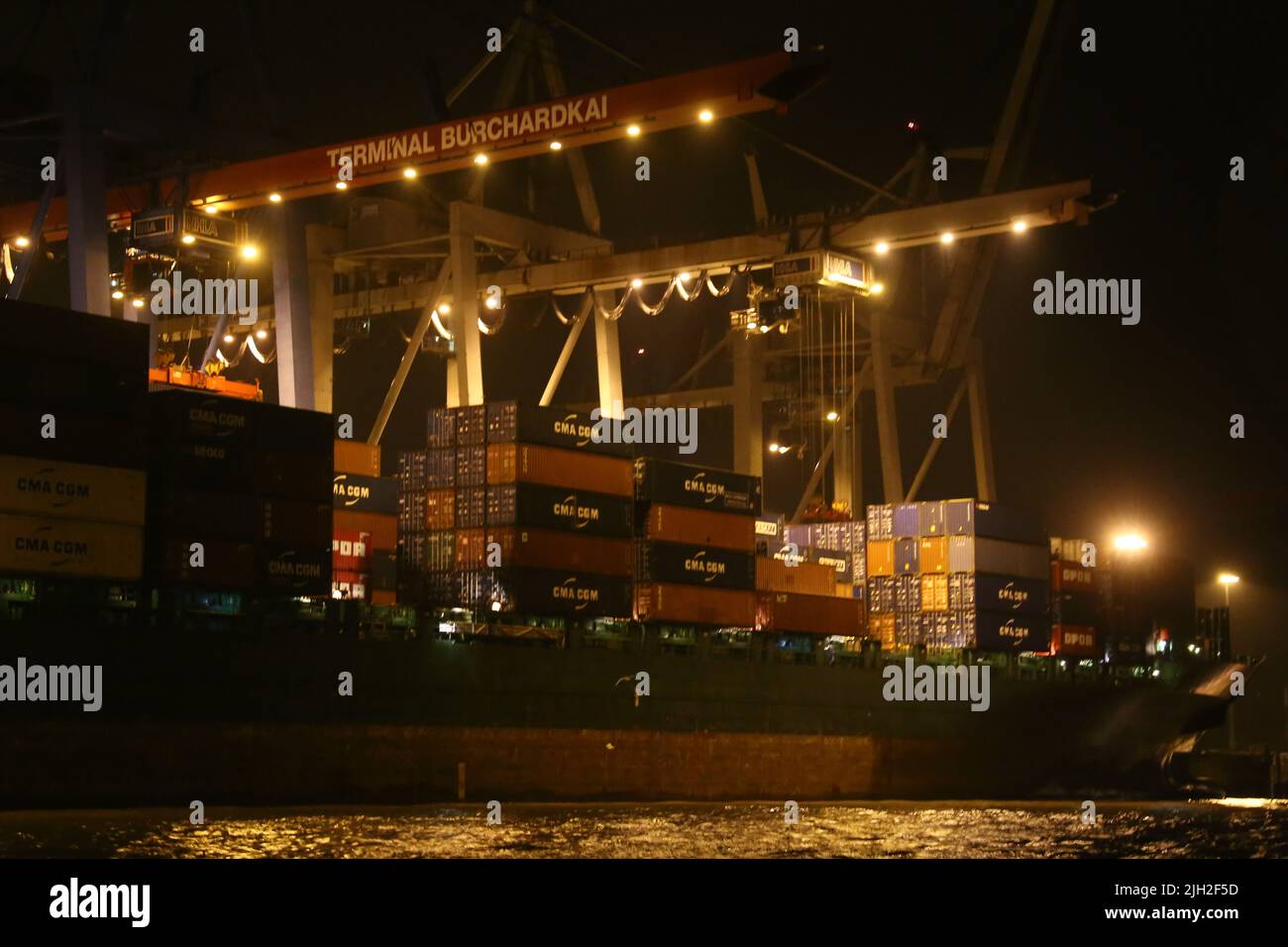 Beim Be- und Entladen der Container-Schiffe gibt es keine Pause. Nachts tauchen starke Scheinwerfer die Container-Brücken und Kais in gleißendes Licht. Stock Photo