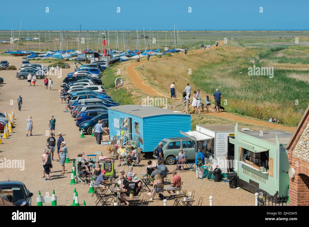 Summer Norfolk coast, view on a summer afternoon of people relaxing at food stalls beside the North Norfolk Coast Path in Blakeney Village, England Stock Photo