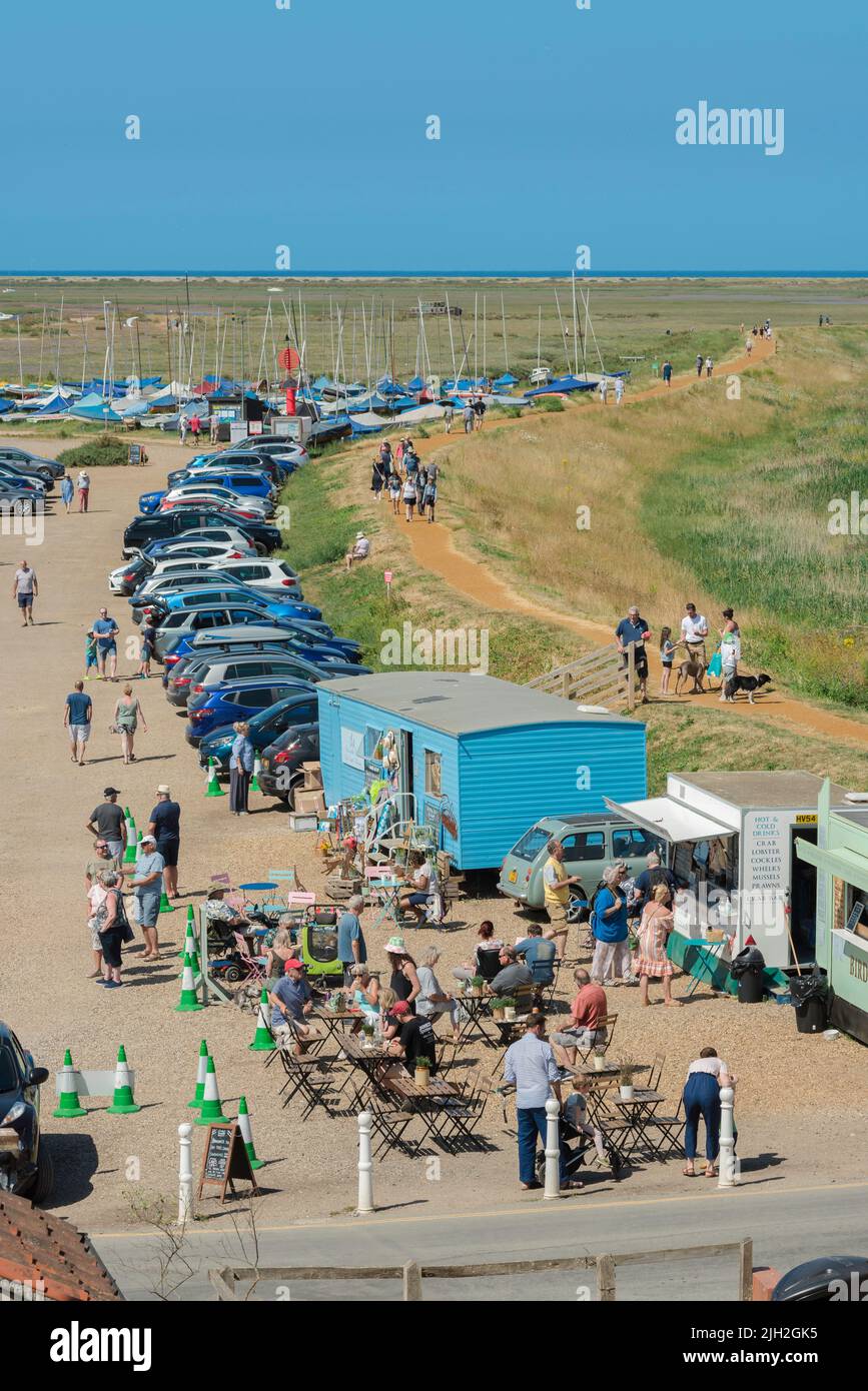 Summer England coast, view on a summer afternoon of people relaxing at food stalls beside the North Norfolk Coast Path in Blakeney Village, England Stock Photo