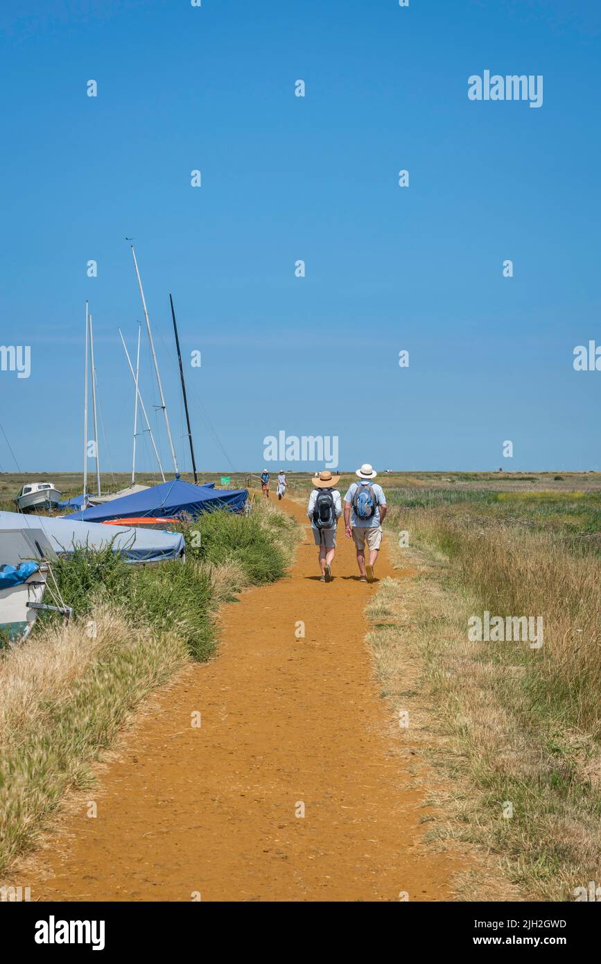 Couple walking summer, rear view of a mature couple walking the North Norfolk Coast Path on a hot summer day near Blakeney, Norfolk, England, UK Stock Photo