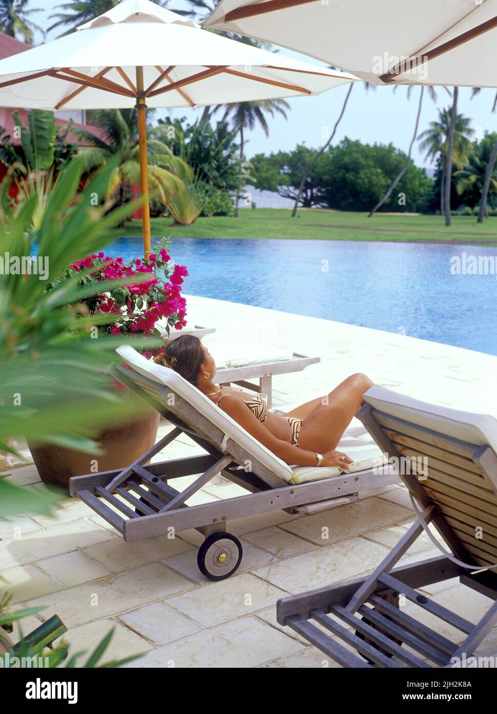 A young French tourist rests poolside at a hotel pool. Cap Est , Martinique, the Caribbean Stock Photo