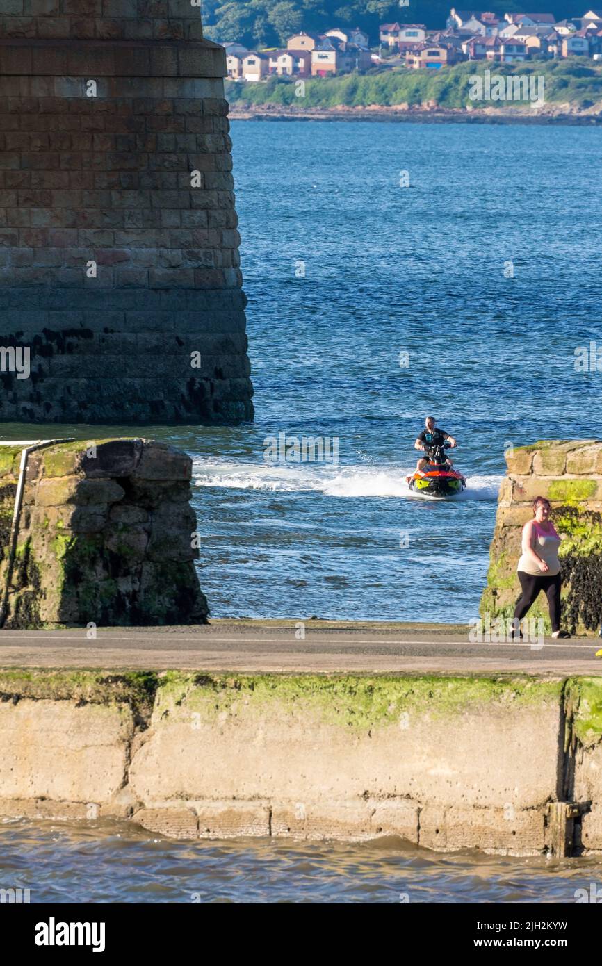 One Man on a Jet Ski causing some sea spray on the Firth of Forth, South Queensferry, Scotland Stock Photo