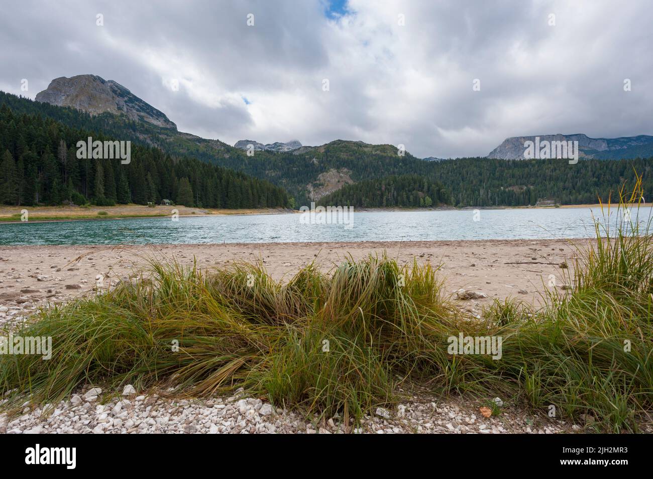 The Black Lake in Durmitor National Park with a bunch of grass in the foreground and mountains in the background. Municipality of Žabljak,  Macedonia. Stock Photo