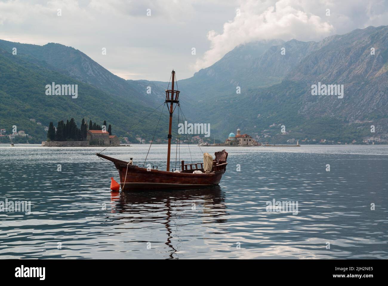 A moored boat in front of the islets of St. George and Our Lady of the Rocks near old town Perast at the Bay of Kotor, Montenegro Stock Photo
