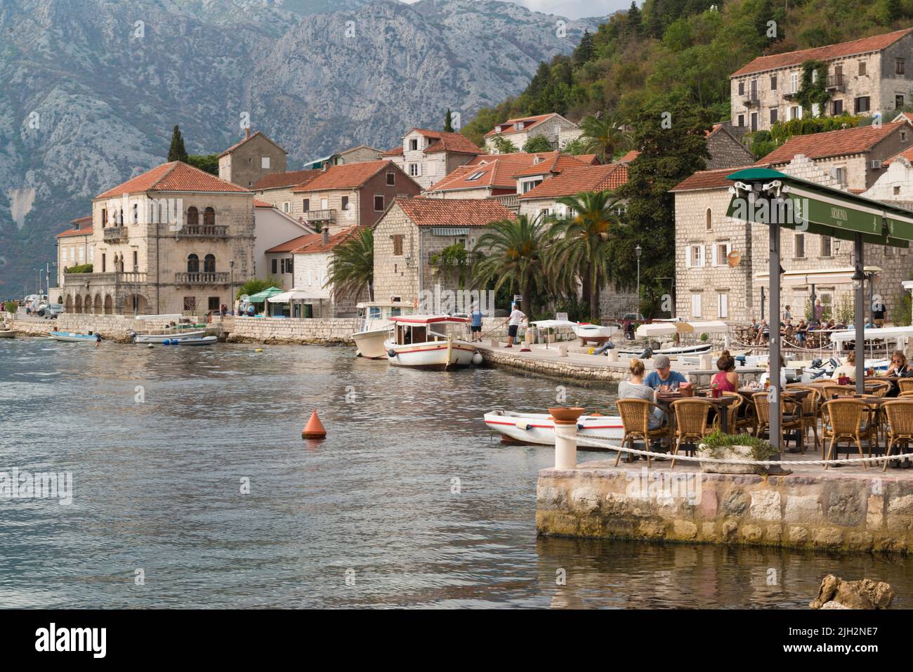 Waterfront of the old town Perast with terrace and some moored small boats at the Bay of Kotor, Montenegro. Stock Photo