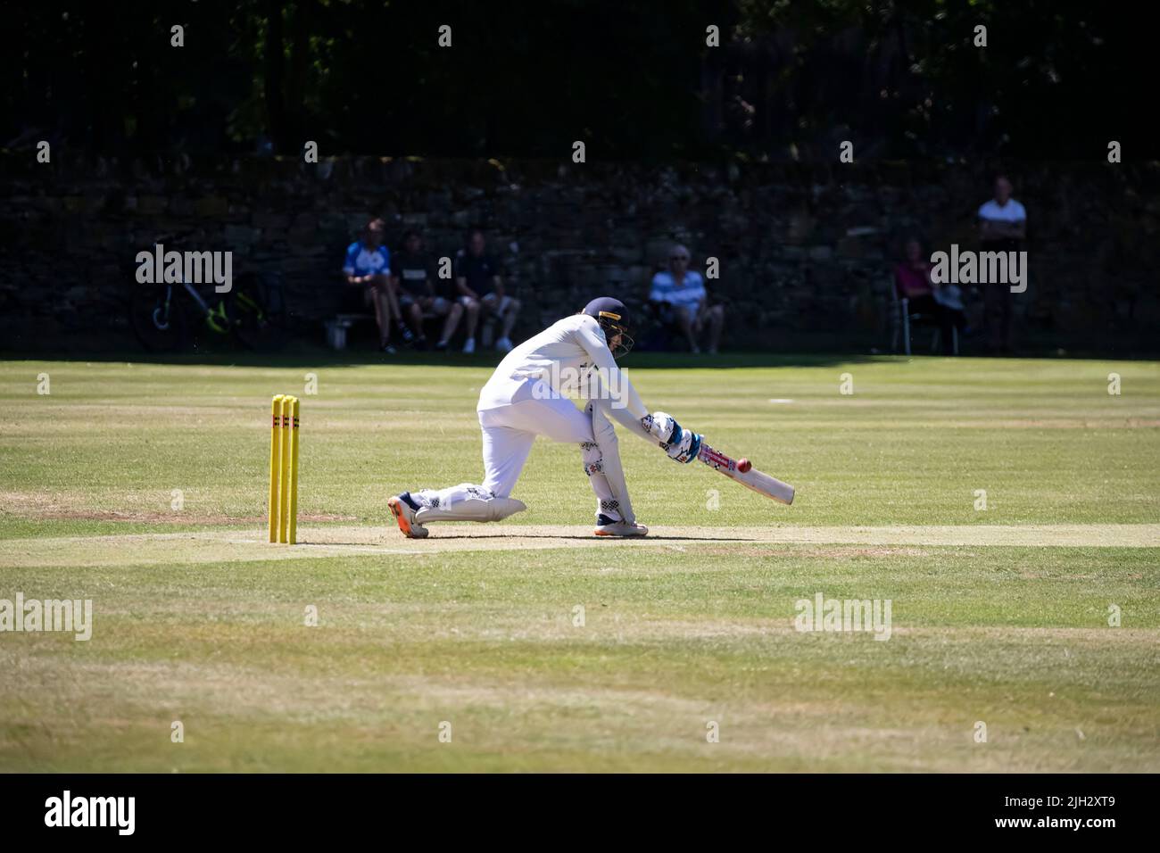 Left handed batsman sweeping the ball to the leg side during a local summer league cricket knockout match in Huddersfield, West Yorkshire Stock Photo