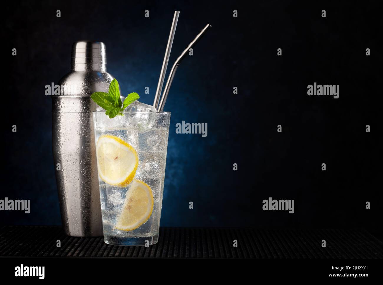 Cocktail shaker and gin tonic cocktail on dark background with copy