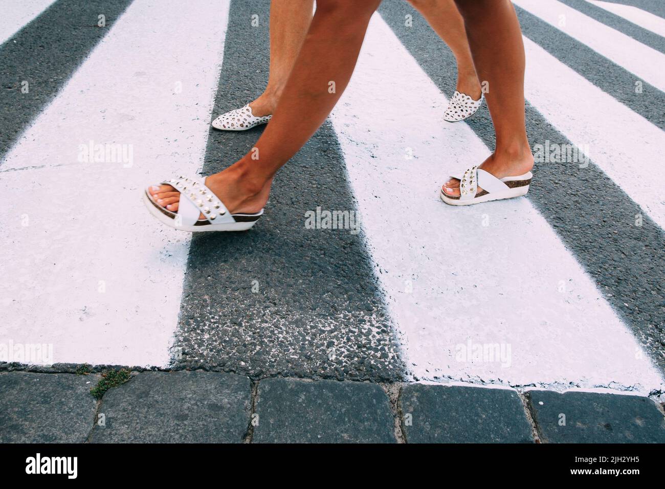 Female legs in white shoes going on zebra Stock Photo