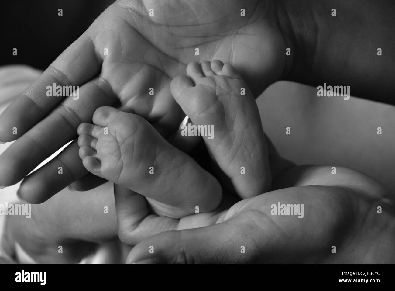 Mother holding newborn baby's feet in black and white Stock Photo
