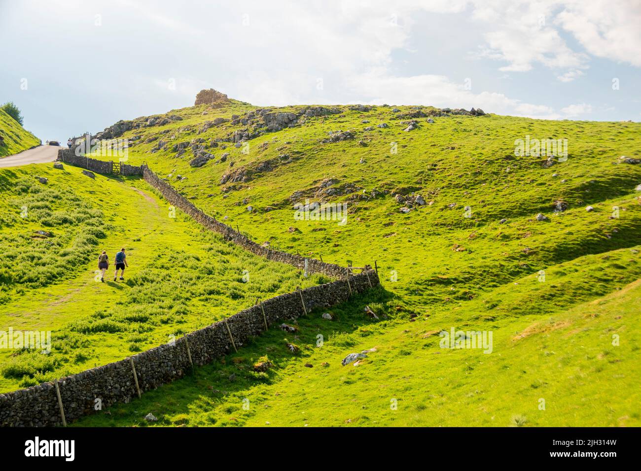 Derbyshire, UK – 5 April 2018: Two tiny people climbing the steep hill at Winnats Pass in the Peak District National Park Stock Photo