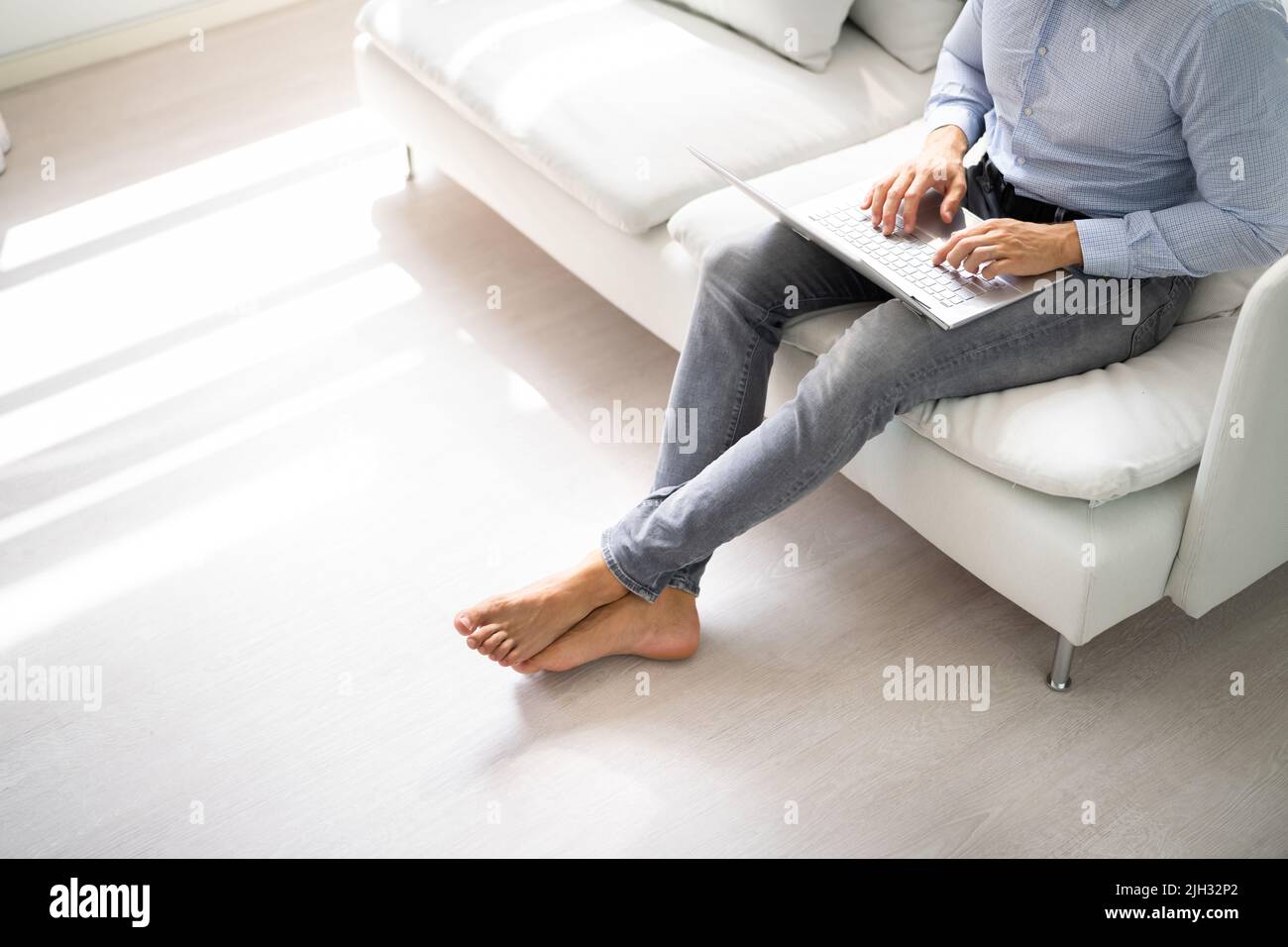 Floor Heating. Barefoot Man Person Using Computer In Room Stock Photo