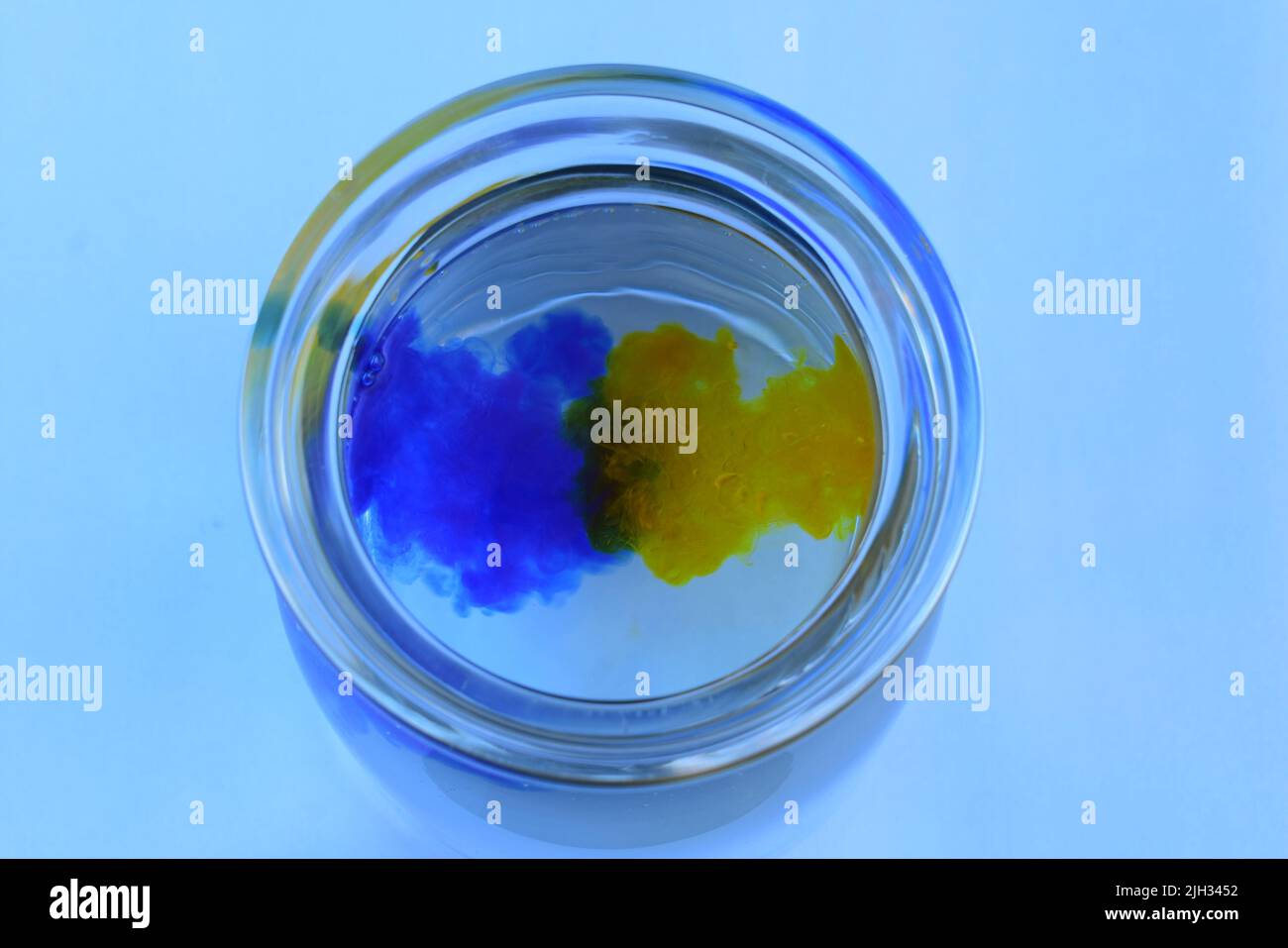 Blue And Yellow Food Colouring Mixing Together Stock Photo Alamy