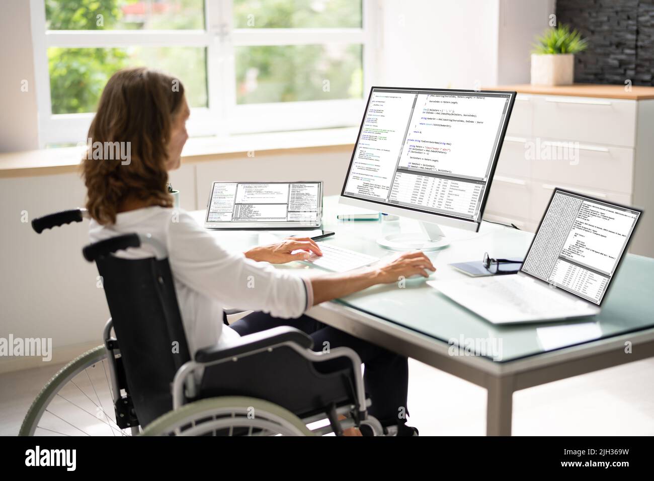 Programmer Woman Coding On Multiple Computer Screens Stock Photo - Alamy