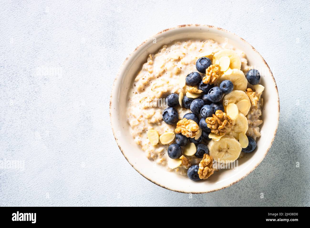 Oatmeal porrige in craft bowl at white background. Stock Photo