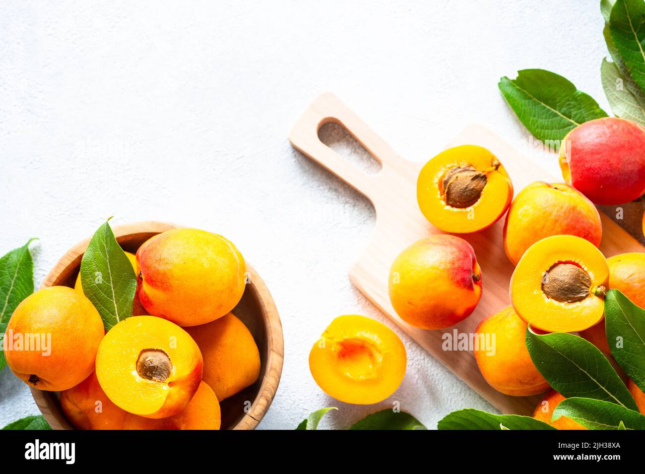 Fresh apricots with green leaves at white. Stock Photo