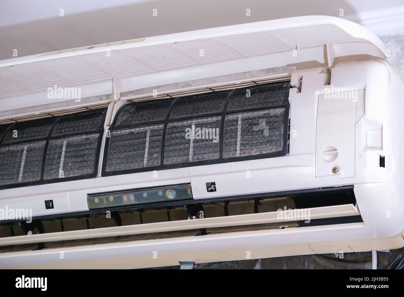 The man takes out filters from the air conditioner for cleaning. Split