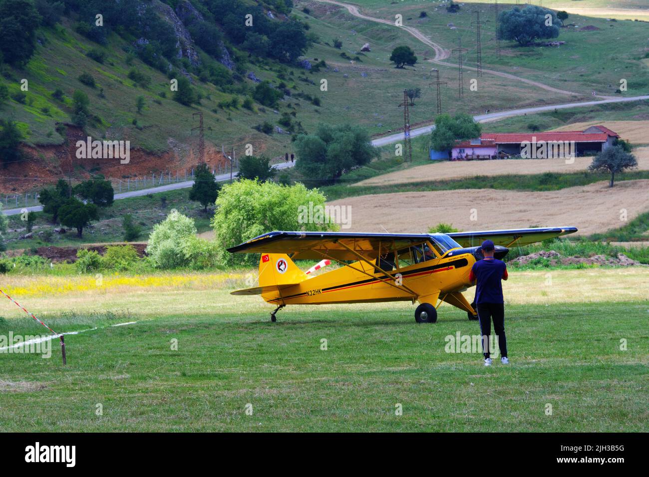 Small yellow propeller airplane on grass at a sunny day and people ...