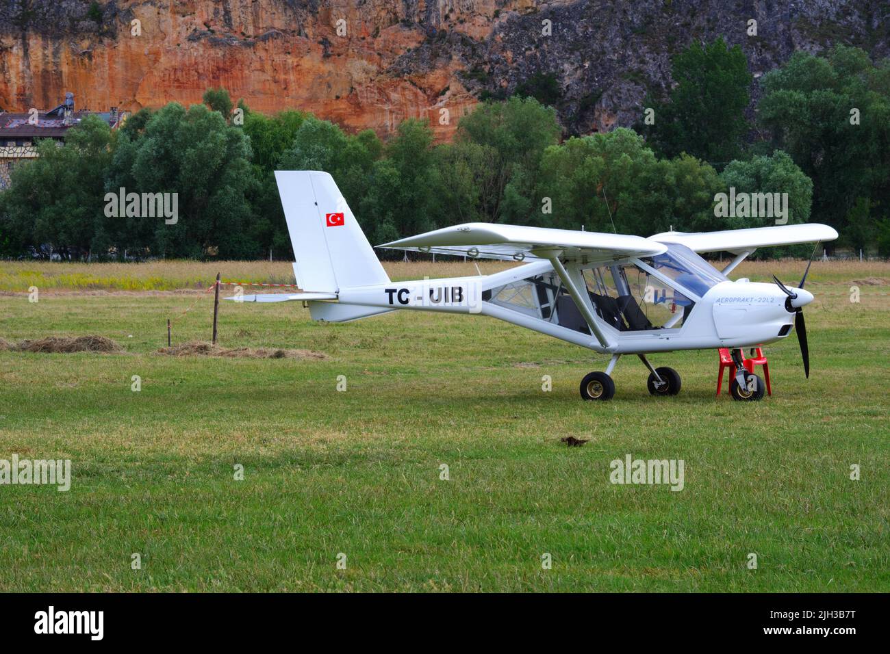 White single-engine airplane on grass in nature Stock Photo