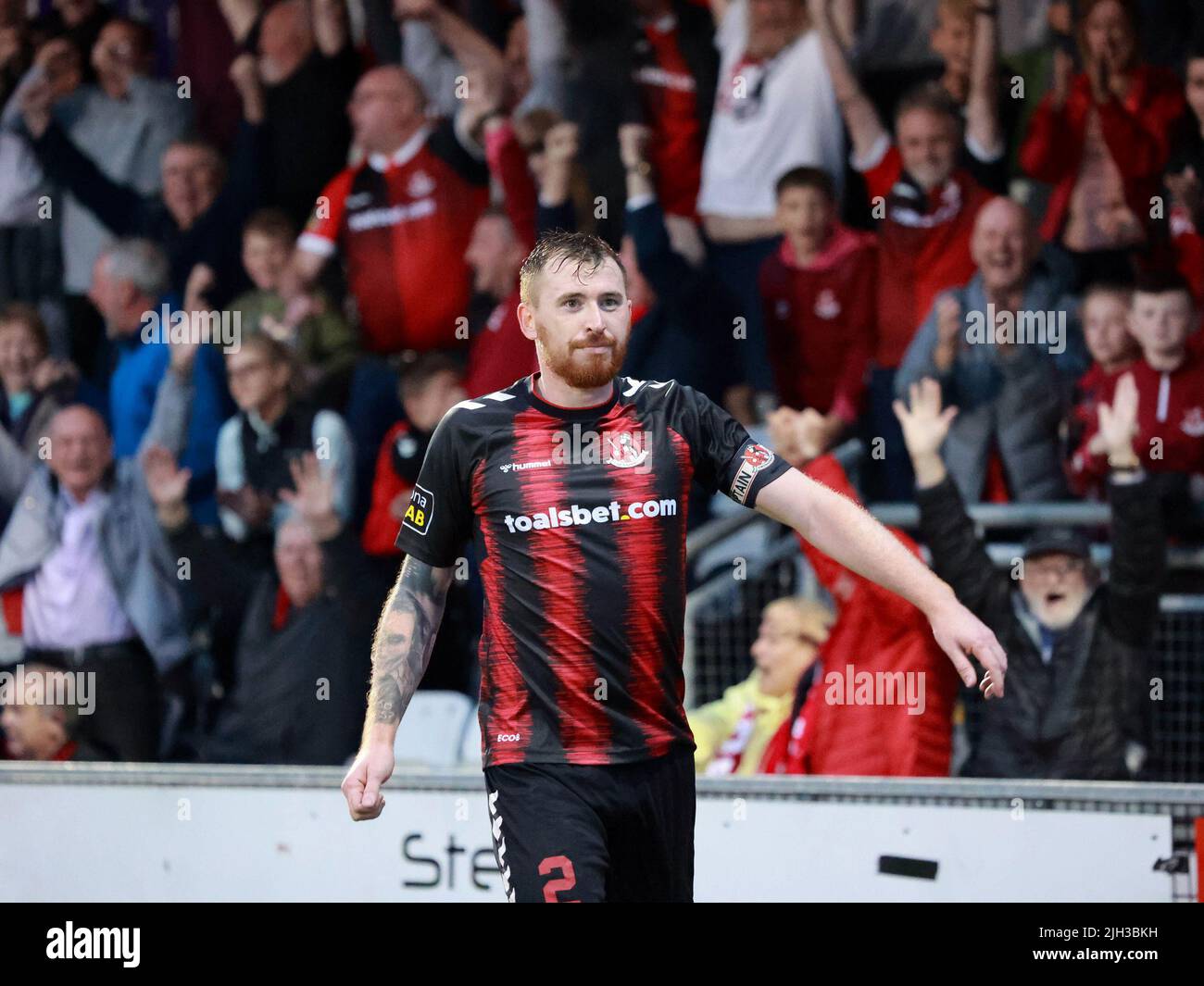 Seaview, Belfast, Northern Ireland, UK. 14 July 2022. UEFA Conference League First Qualifying Round  (second leg) – Crusaders v Magpies. Action from tonight's game at Seaview (Crusaders in red/black). Credit: Crusaders captain Billy Joe Burns (2) scoring and celebrating the winning goal. CAZIMB/Alamy Live News. Stock Photo