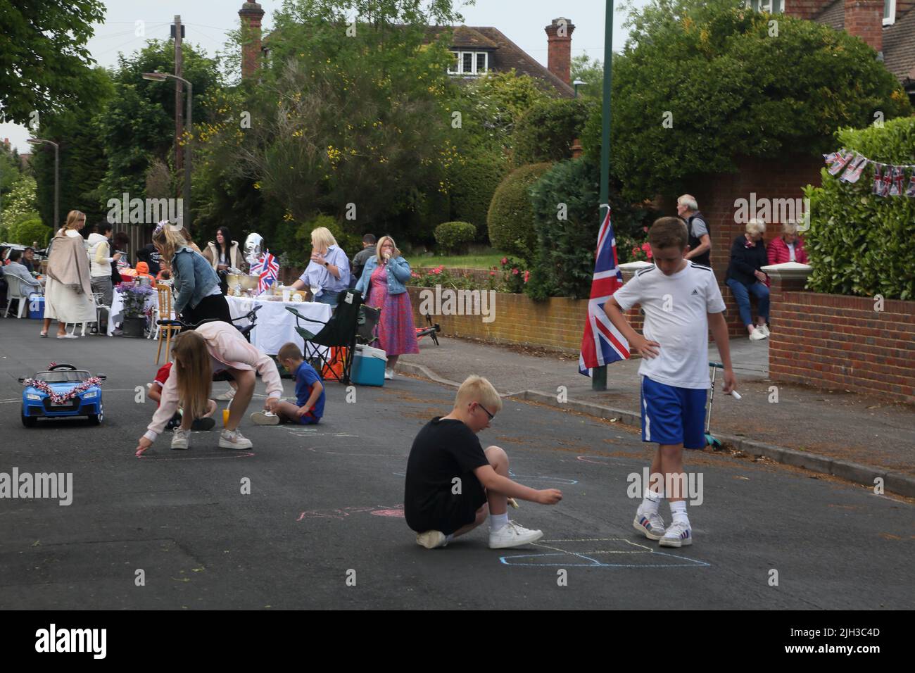 Children Drawing on road with Chalk at Street Party Celebrating Queen Elizabeth II Platinum Jubilee Surrey England Stock Photo