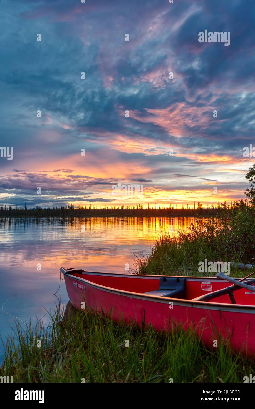 Red canoe parked at cabin under the summer midnight sun, along shoreline of Great Bear Lake, Northwest Territories, Canada. Stock Photo