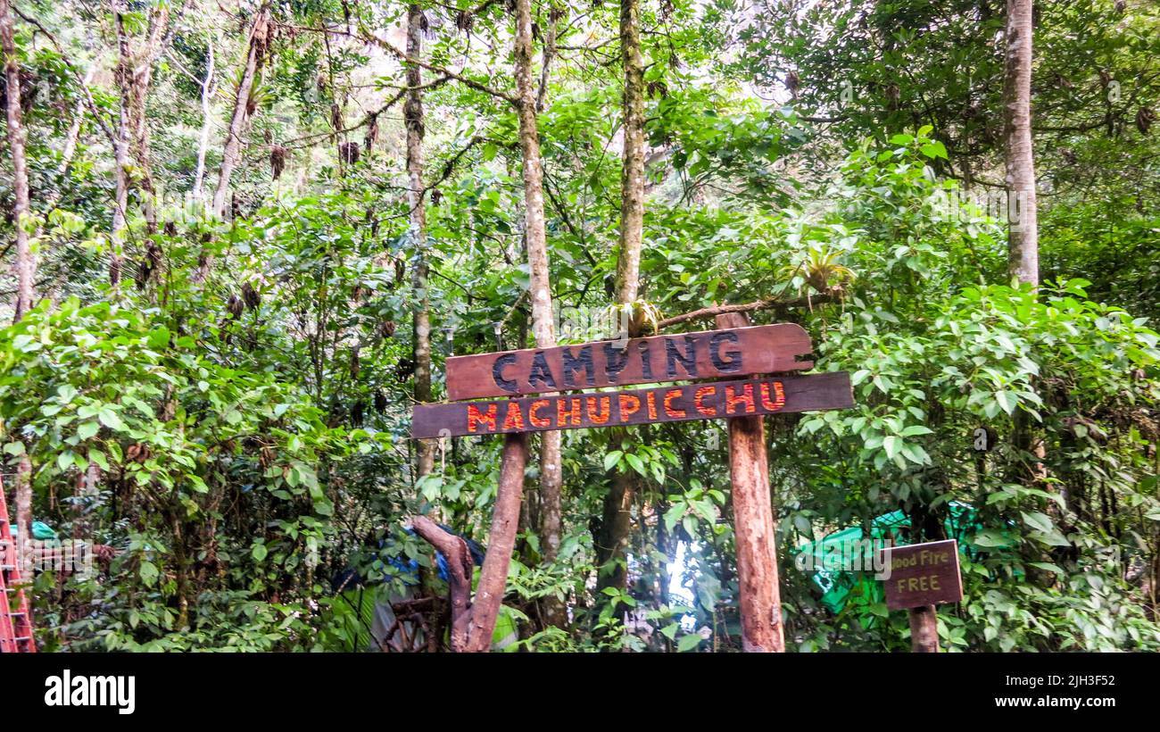 Camping Machu Picchu wood sign in front of green tropical trees. Natural and historical background with copy space. Machu Picchu is an Incan citadel. Stock Photo