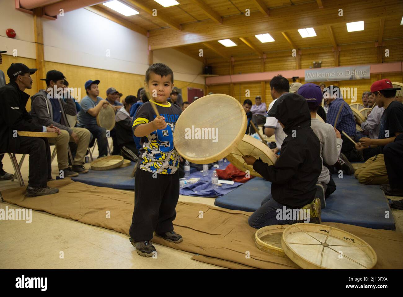 Young Dene boy playing a drum at community handgames, in the northern Indigenous community of Deline, Northwest Territories, Canada Stock Photo