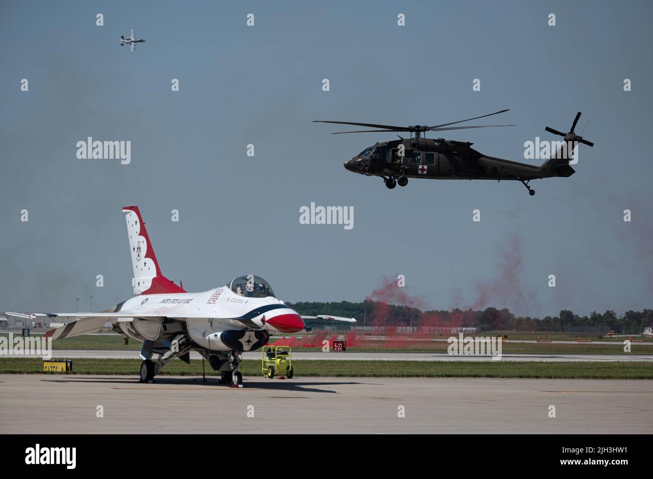 A UH60 Blackhawk helicopter flies over an F16 Fighting Falcon