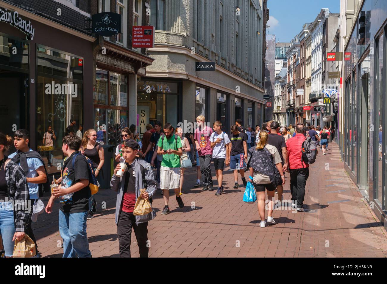 Amsterdam, The Netherlands - 23 June 2022: People walking on narrow street with many stores Stock Photo