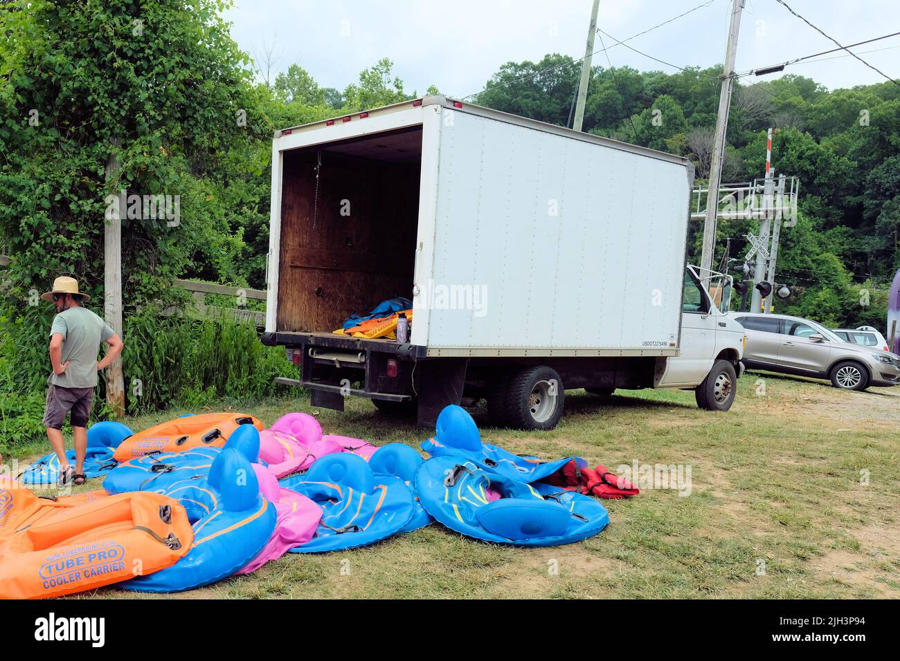 Effort, hard work, the insurmountable weight of a difficult task ahead; man with the job of inflating large quantity of vinyl tubes for river tubing. Stock Photo