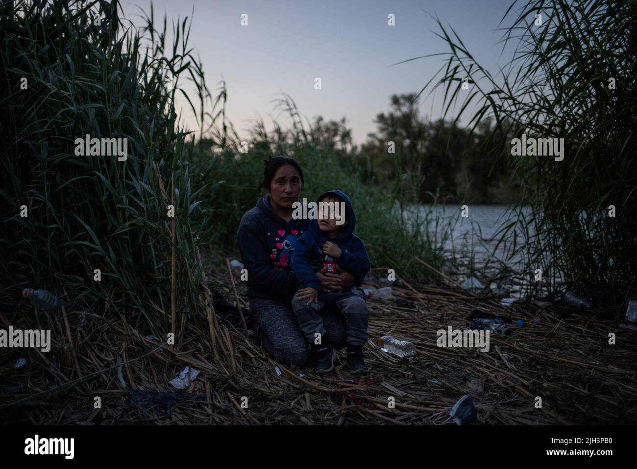 Nacilia, any asylum seeking migrant from Guatemala, holds her three year old son Alessandro, as they await on a sandbar in the midst of Rio Bravo del Norte, also known as the Rio Grande river, to be smuggled into the United States from Ciudad Miguel Aleman, Mexico July 13, 2022. REUTERS/Adrees Latif Stock Photo