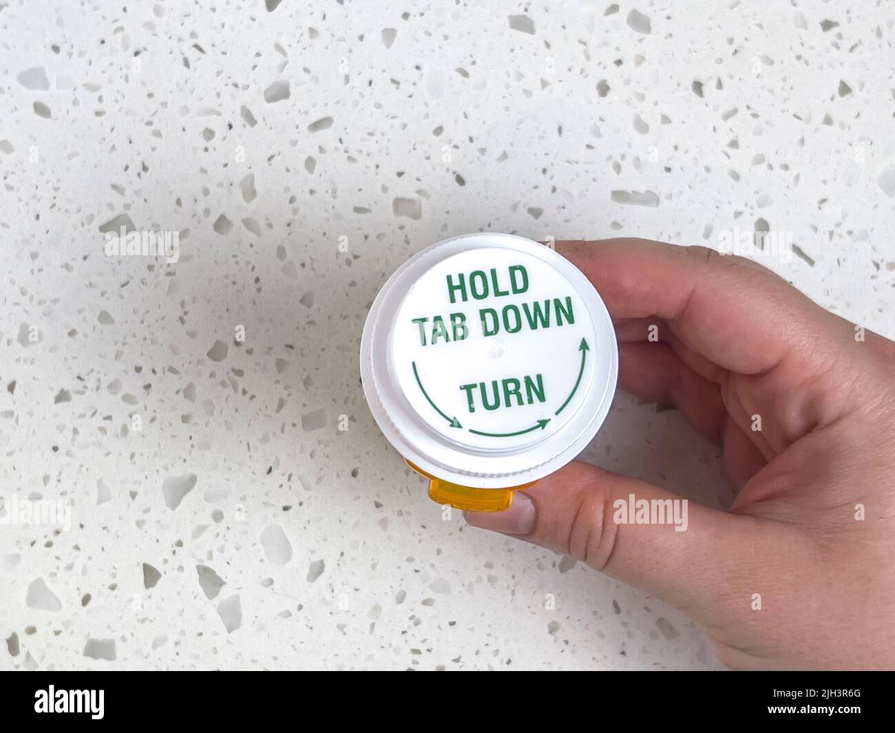 Top down view of a person holding a pill bottle against a white counter top Stock Photo
