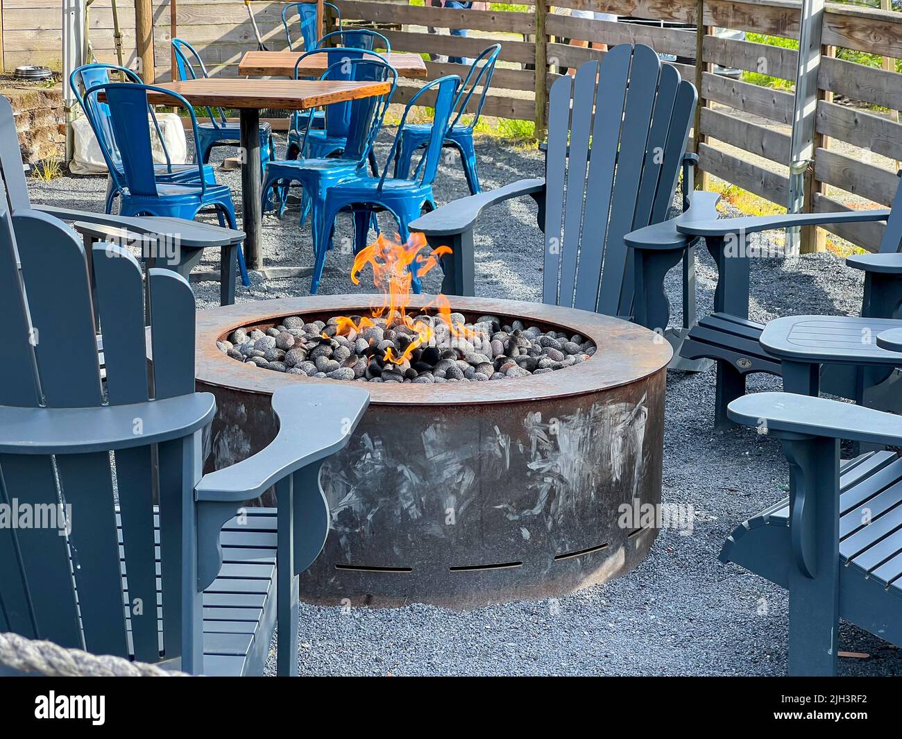 Close up view of adirondack chairs circling a fire pit filled with ...